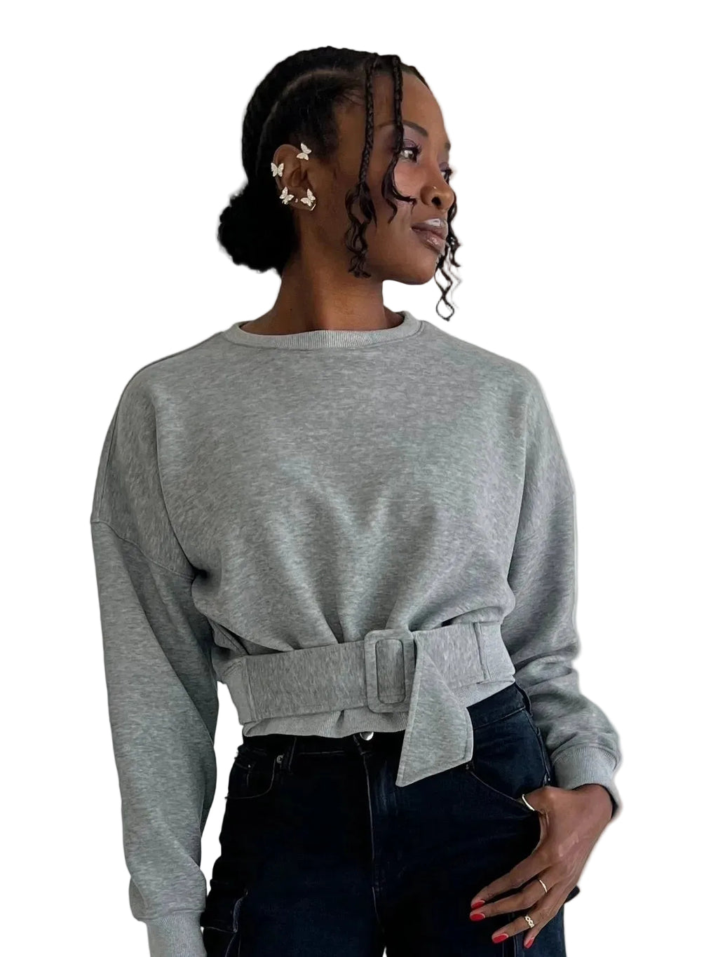 Woman wearing a gray sweater with a belt, standing against a plain background