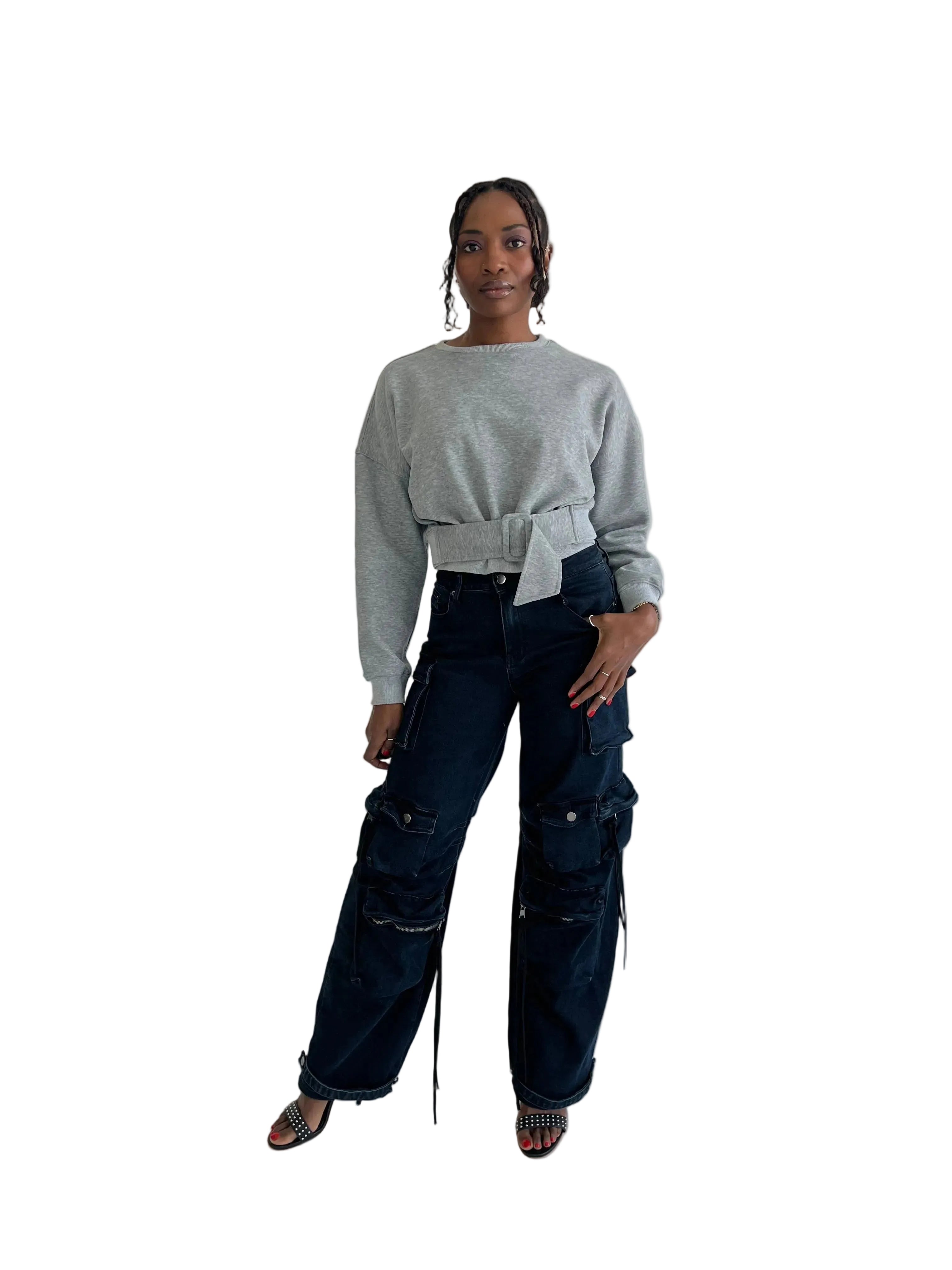 Person wearing a gray sweater and dark blue cargo pants on a white background