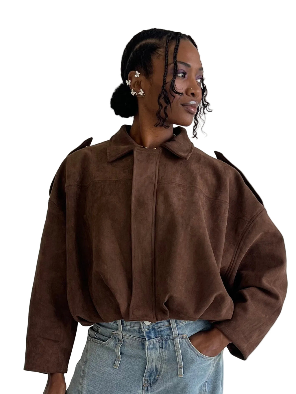 Woman wearing a brown suede jacket and blue jeans against a plain background