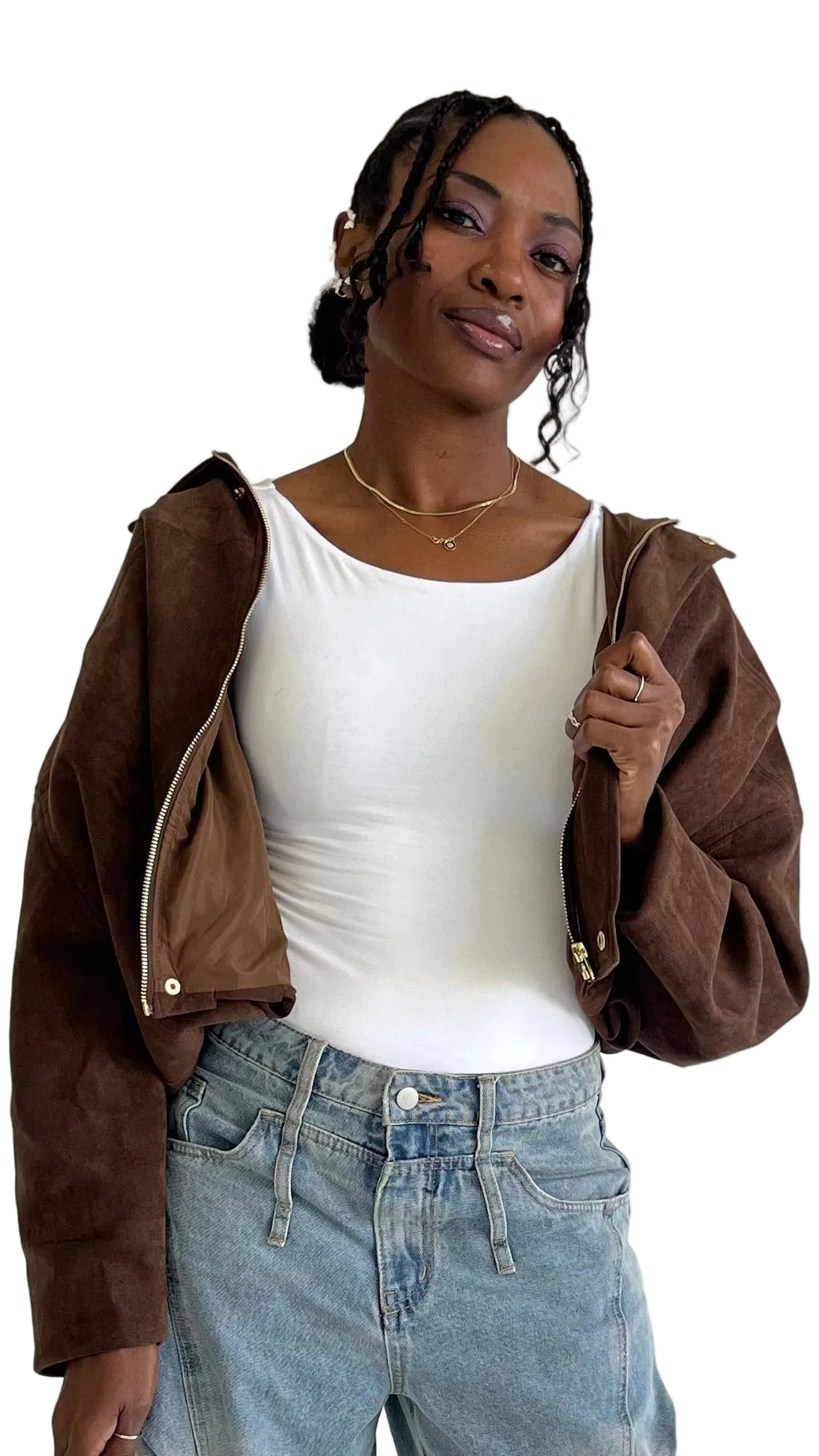 Woman wearing a brown jacket, white top, and blue jeans against a plain background