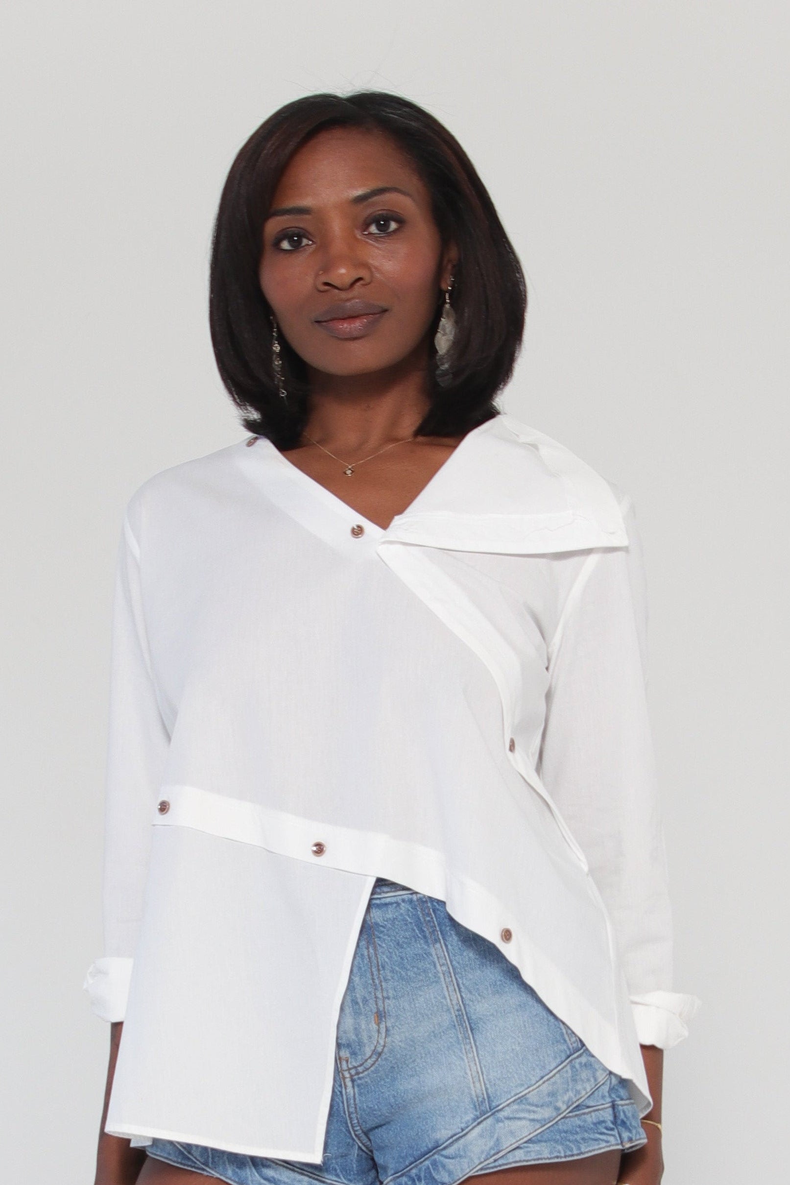 Person wearing a white shirt and denim shorts on a light gray background