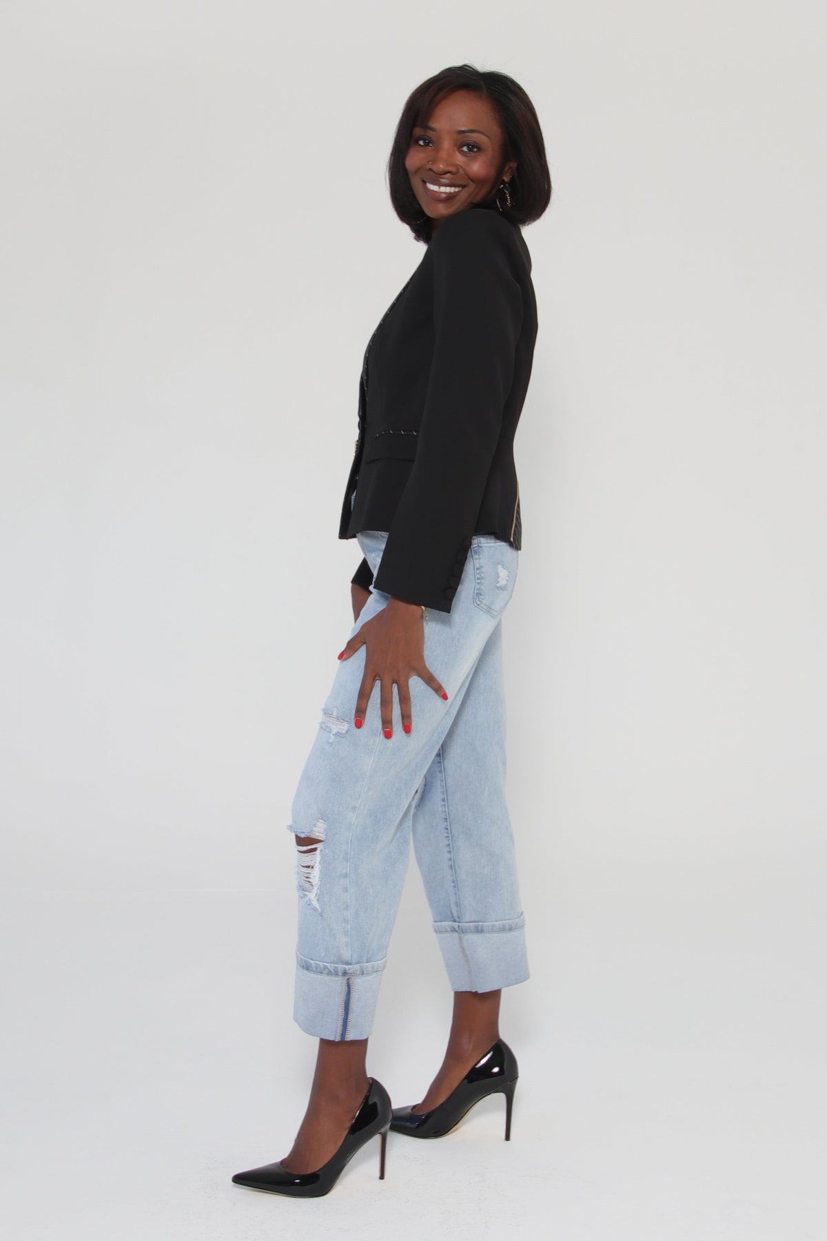 Person wearing a black jacket and light blue jeans on a white background