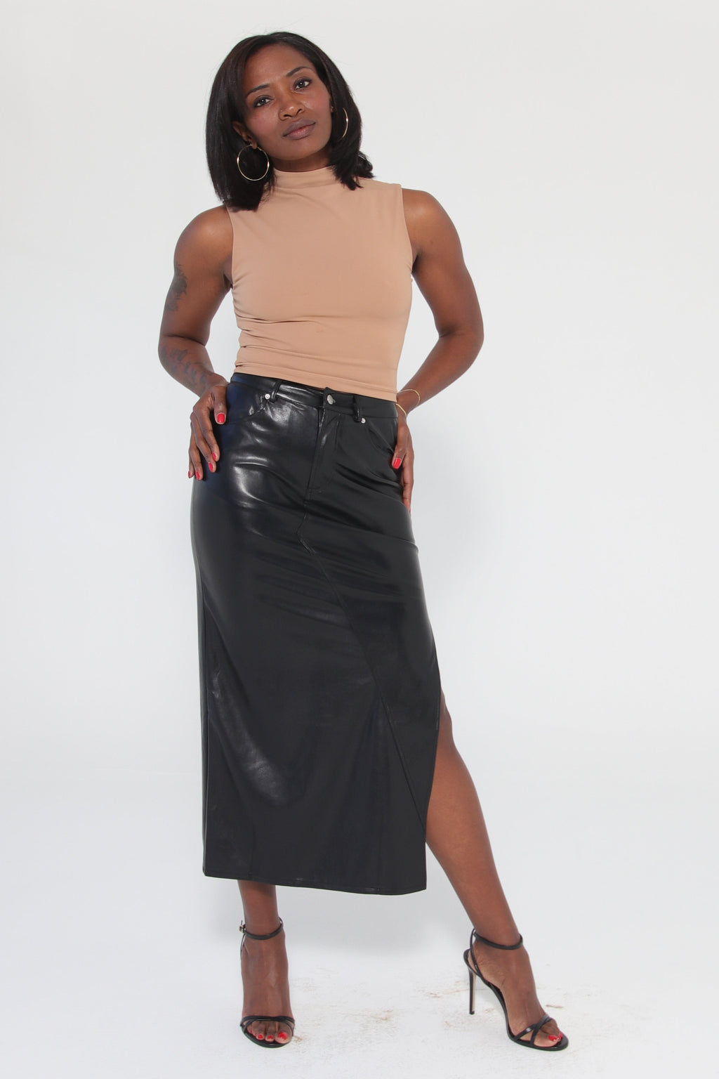 Woman wearing a black leather skirt and beige top on a white background