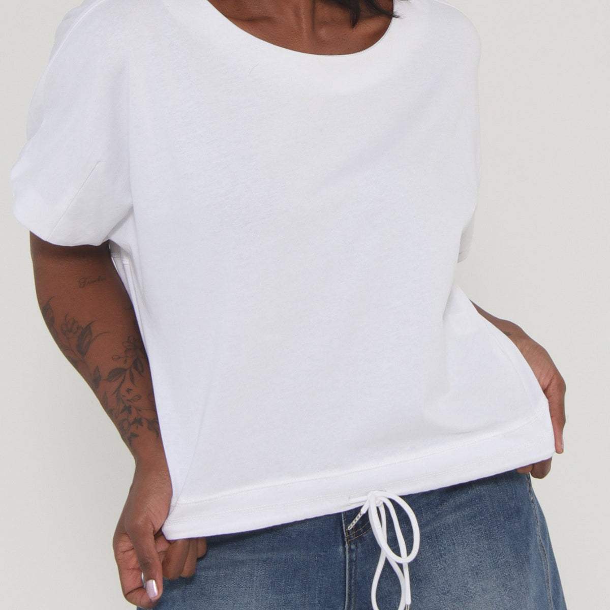 Person wearing a white shirt and blue jeans on a plain background