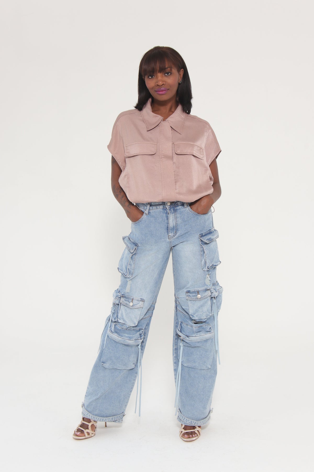 Person wearing light blue ripped jeans and a pink top on a white background